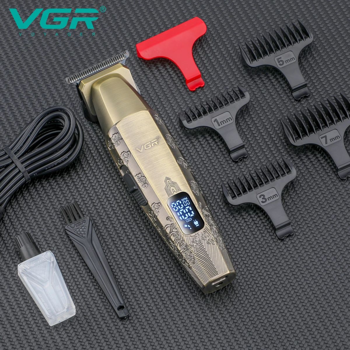 flat lay product display of vgr v-265 professional grooming trimmer with detailed gold engraving body on a black textured surface including red blade guard four black guide combs 1mm 3mm 5mm 7mm usb charging cable cleaning brush and blade oil bottle