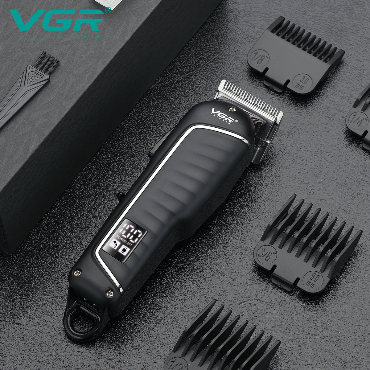 Black VGR V-683 professional hair cutting machine placed on a table with attachment shaving clips and a cleaning brush.